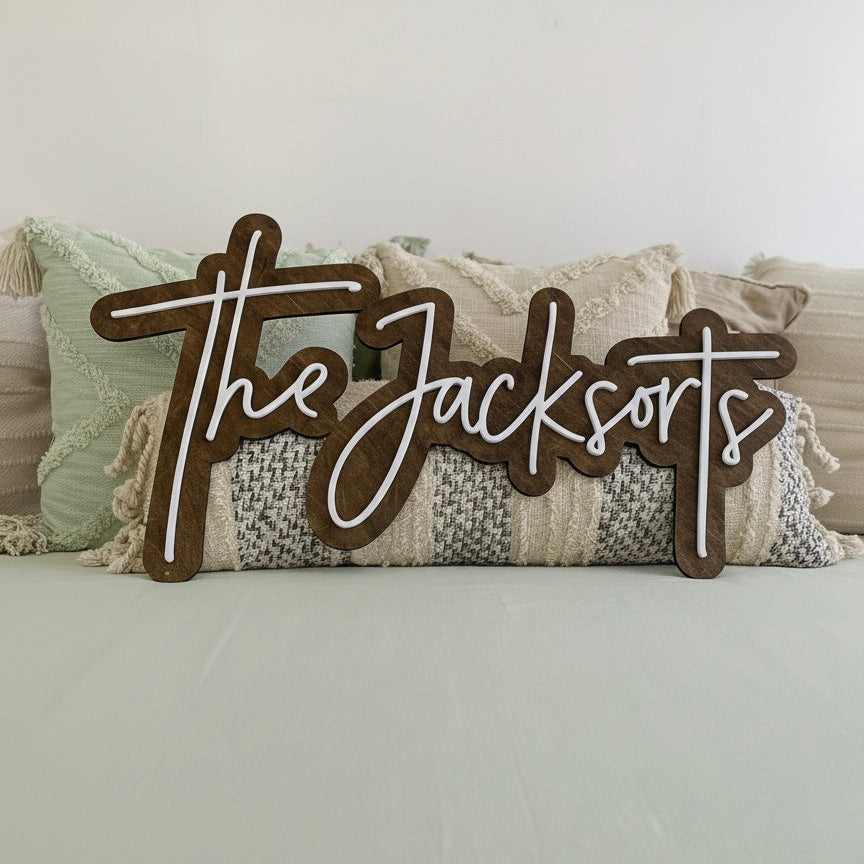 Decorative last name wooden sign with 'The Jacksons' on a couch with pillows in the background