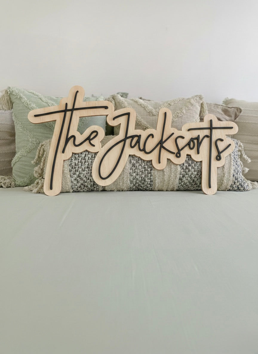 Front view of a custom last name wooden sign positioned against bohemian styled pillows.