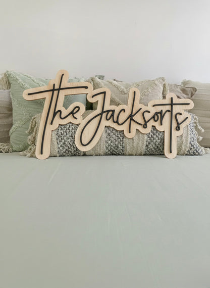 Front view of a custom last name wooden sign positioned against bohemian styled pillows.