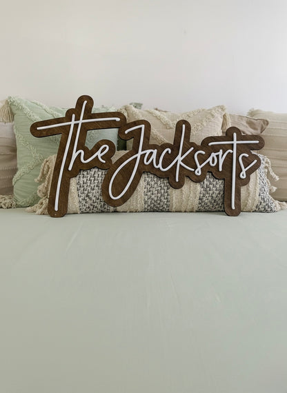 A custom last name wooden sign positioned against bohemian styled pillows.