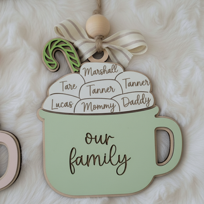 Decorative sign shaped like a mug with family names on a soft white background