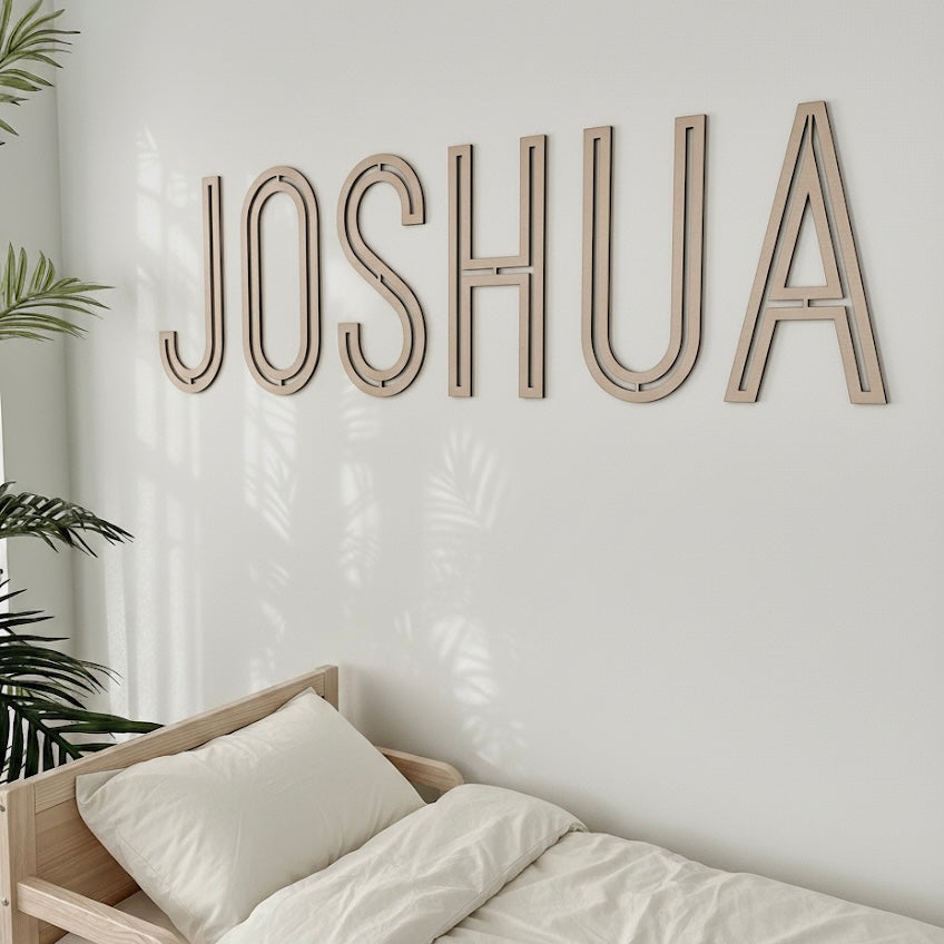 Wooden name 'JOSHUA' on a wall above a bed with white bedding.